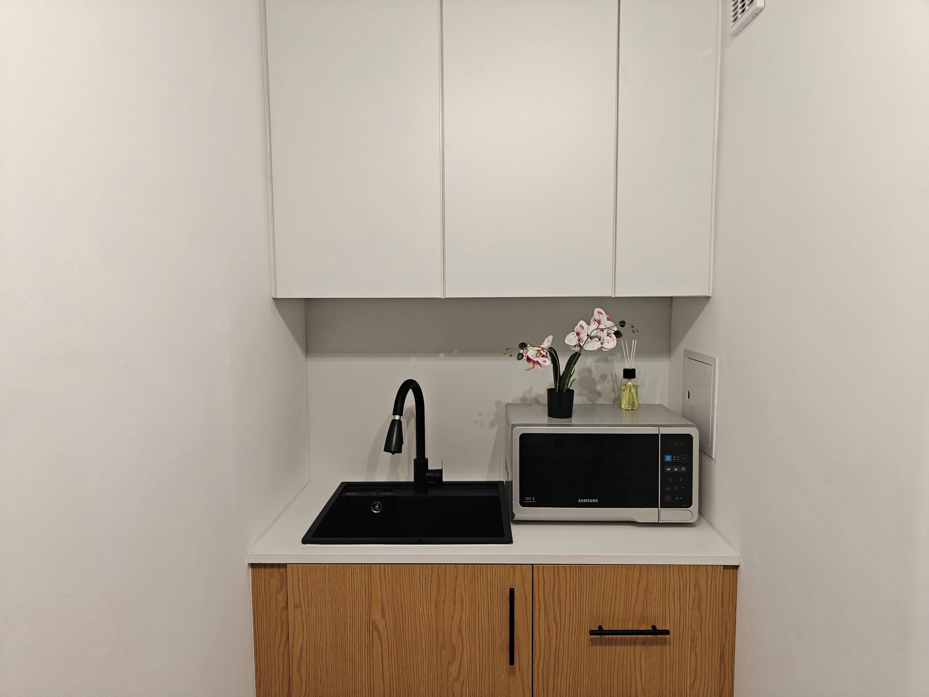 A compact kitchen with a sink, a microwave, and a cabinet.