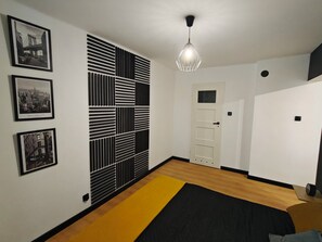 Quarto com cama, parede listrada em preto e branco, porta e luminária pendente.