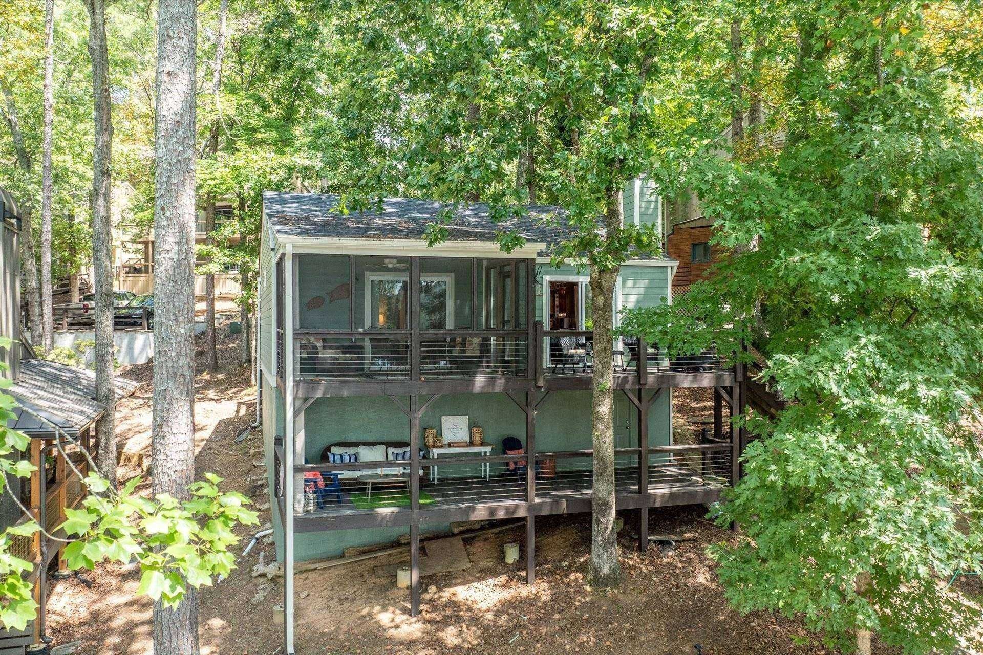 A multi-level cabin with a balcony, surrounded by trees.