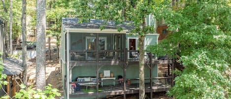 Eine mehrstöckige Hütte mit einem Balkon, umgeben von Bäumen.