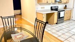 A modern kitchen with wooden cabinets, a built-in oven, and a glass dining table with chairs.