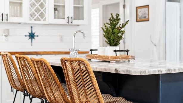 A kitchen with white cabinets, a marble island, wicker chairs, a potted plant, and a star-shaped light fixture. - Luxury Retreat |Pool| Game Room|Billards|AirHockey (St. Augustine)