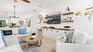A modern living room with a sofa, coffee table, and television. - Luxury Retreat |Pool| Game Room|Billards|AirHockey (St. Augustine)