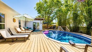 A wooden deck with a swimming pool, lounge chairs, and a covered seating area. - Luxury Retreat |Pool| Game Room|Billards|AirHockey (St. Augustine)