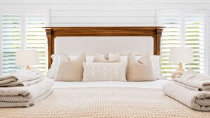 A neatly made bed with a wooden headboard, multiple pillows, and a folded blanket on the floor. - Luxury Retreat |Pool| Game Room|Billards|AirHockey (St. Augustine)
