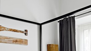 A modern bedroom with a bed, pillows, a nightstand, a lamp, and a window with curtains. - The Mariner by Experience Metung (Metung)