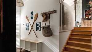 A staircase with wooden steps, a white wall with numbers and a woven basket, and a bench. - The Mariner by Experience Metung (Metung)