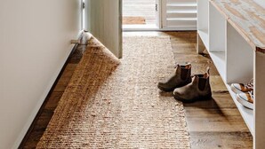 A hallway with a wooden bench, a door leading outside, and a wall-mounted number sign. - The Mariner by Experience Metung (Metung)