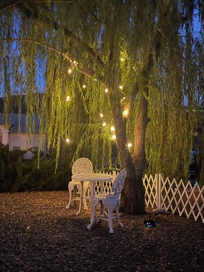 An outdoor seating area with a bench and a table under a tree, surrounded by a wooden fence. - 2-bedroom Ivory Wellness Retreat Prescott Lakes (Prescott)