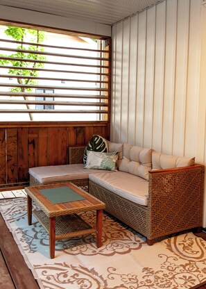 A room with a wicker sofa, a small table, and a patterned rug.
