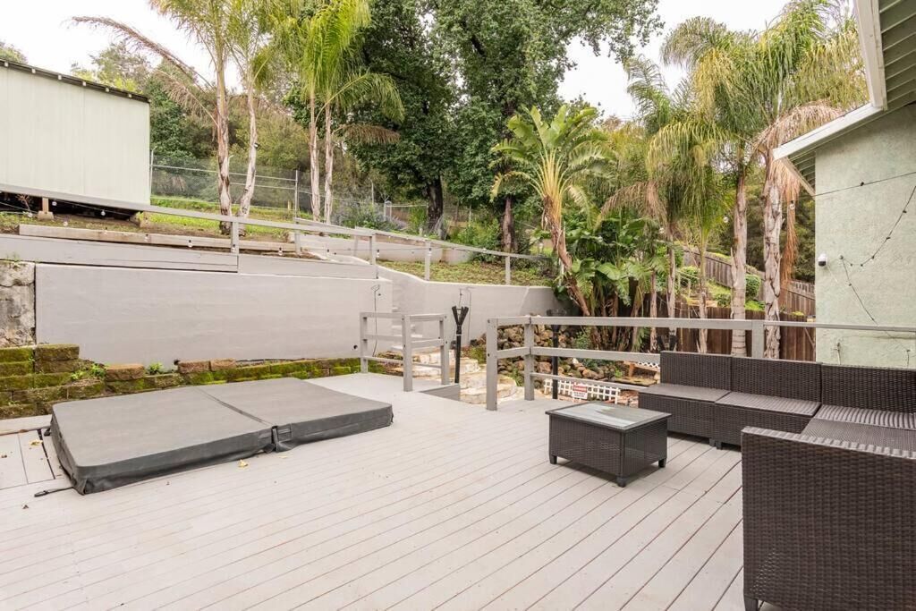 A deck with outdoor furniture, a ramp, and a view of a road and greenery.
