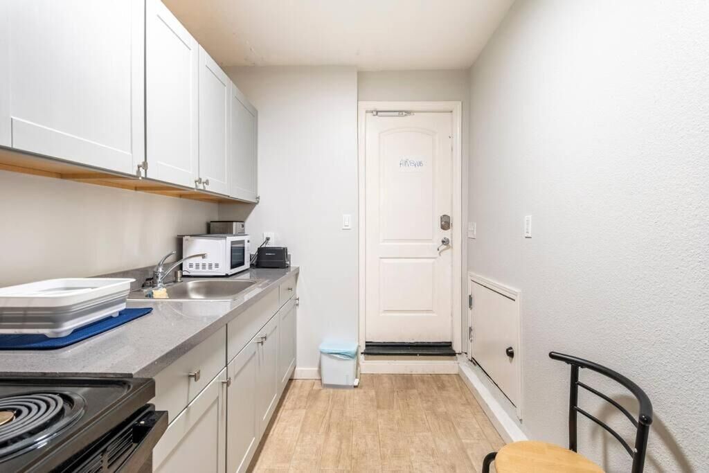 A compact kitchen with white cabinets, a microwave, a sink, and a stove.