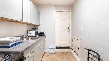 A compact kitchen with white cabinets, a microwave, a sink, and a stove.