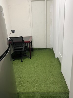 Un pequeño espacio de oficina con un escritorio, una silla y un refrigerador.