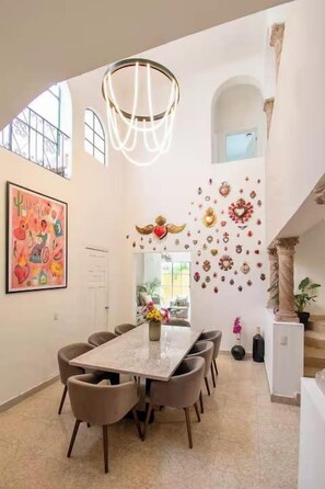 A dining area with a long table, chairs, and a chandelier. - Casa Corazón | 5BR Oasis in La Condesa (Mexico City)