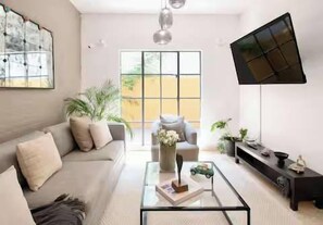 A modern living room with a sofa, coffee table, and a flat-screen TV mounted on the wall. - Casa Corazón | 5BR Oasis in La Condesa (Mexico City)
