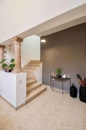 A modern interior with a staircase, a small table with plants, and a black bag on the floor. - Casa Corazón | 5BR Oasis in La Condesa (Mexico City)