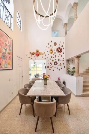 A dining area with a marble table and chairs, a chandelier, and decorative wall art. - Casa Corazón | 5BR Oasis in La Condesa (Mexico City)