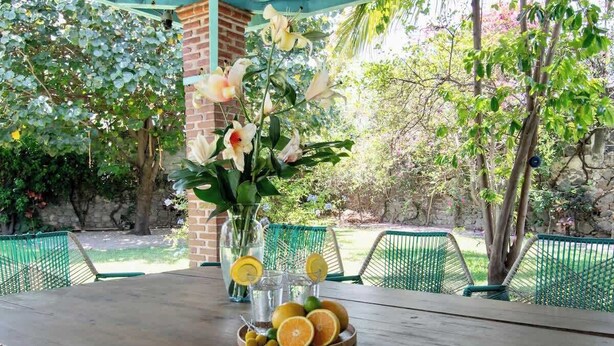 A wooden table with a vase of flowers and a fruit bowl. - Geodesic sanctuary with a heated pool (Chiconcuac)