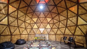 A geodesic dome structure with a central skylight, benches, and a patterned floor. - Geodesic sanctuary with a heated pool (Chiconcuac)