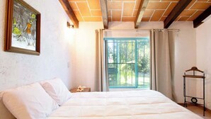 A bedroom with a bed, a window with curtains, a painting on the wall, and a wooden hanger stand. - Geodesic sanctuary with a heated pool (Chiconcuac)