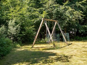 A wooden swing set in a grassy area with dense trees in the background. - "Unelma" -  from the sea by Interhome (Hadsund)