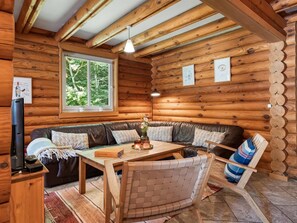 A log cabin interior with a wooden ceiling, a sofa set, a table, and a television. - "Unelma" -  from the sea by Interhome (Hadsund)