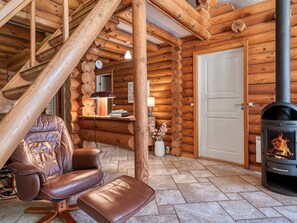A log cabin interior with a leather chair, a fireplace, and a wooden staircase. - "Unelma" -  from the sea by Interhome (Hadsund)