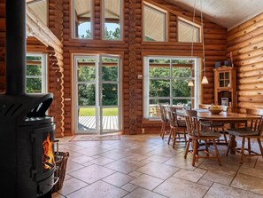 A log cabin interior with a wood-burning stove, dining table, chairs, and large windows. - "Unelma" -  from the sea by Interhome (Hadsund)
