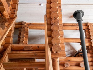 Interior de madera con una estructura central de madera, posiblemente una escalera o un travesaño, rodeado de troncos.