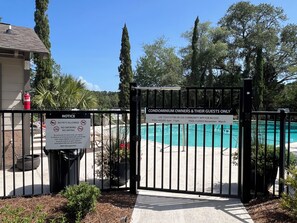 Zona de piscina con acceso restringido, un cartel indica los horarios de apertura y una notificación sobre la prohibición de mascotas y de fumar.