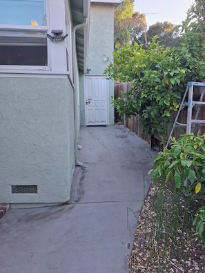 A residential driveway leading to a white door, with a garage door and a wooden fence in the background. -  Adorable Queen Bed Oakland Zoo with Private space and cool AC (Oakland)