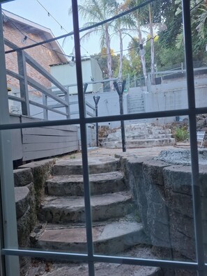 A view through a metal fence with a brick building in the background, stone steps, and a concrete wall. -  Adorable Queen Bed Oakland Zoo with Private space and cool AC (Oakland)