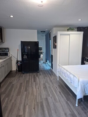 Habitació d'hotel moderna amb cuineta, un llit i un armari.