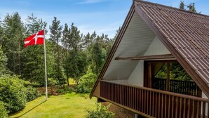 Una casa con tetto spiovente, un portico in legno e un'asta con una bandiera.