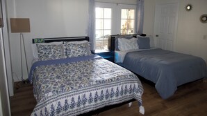 Un dormitorio con dos camas, una ventana con cortinas, una puerta y una lámpara fijada a la pared.