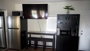 Una cocina compacta con refrigerador, microondas y cafetera.