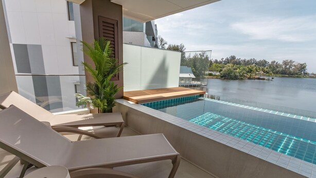 En balkon med swimmingpool, liggestole og en potteplante.