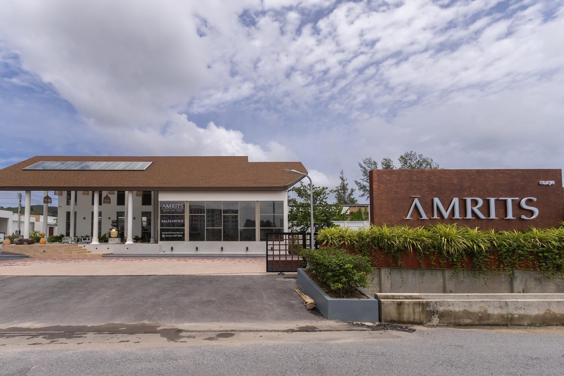 Un bâtiment moderne avec une enseigne indiquant « AMRITS » et un bureau de vente.