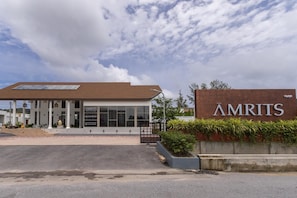 Un bâtiment moderne avec une enseigne indiquant « AMRITS » et un bureau de vente.