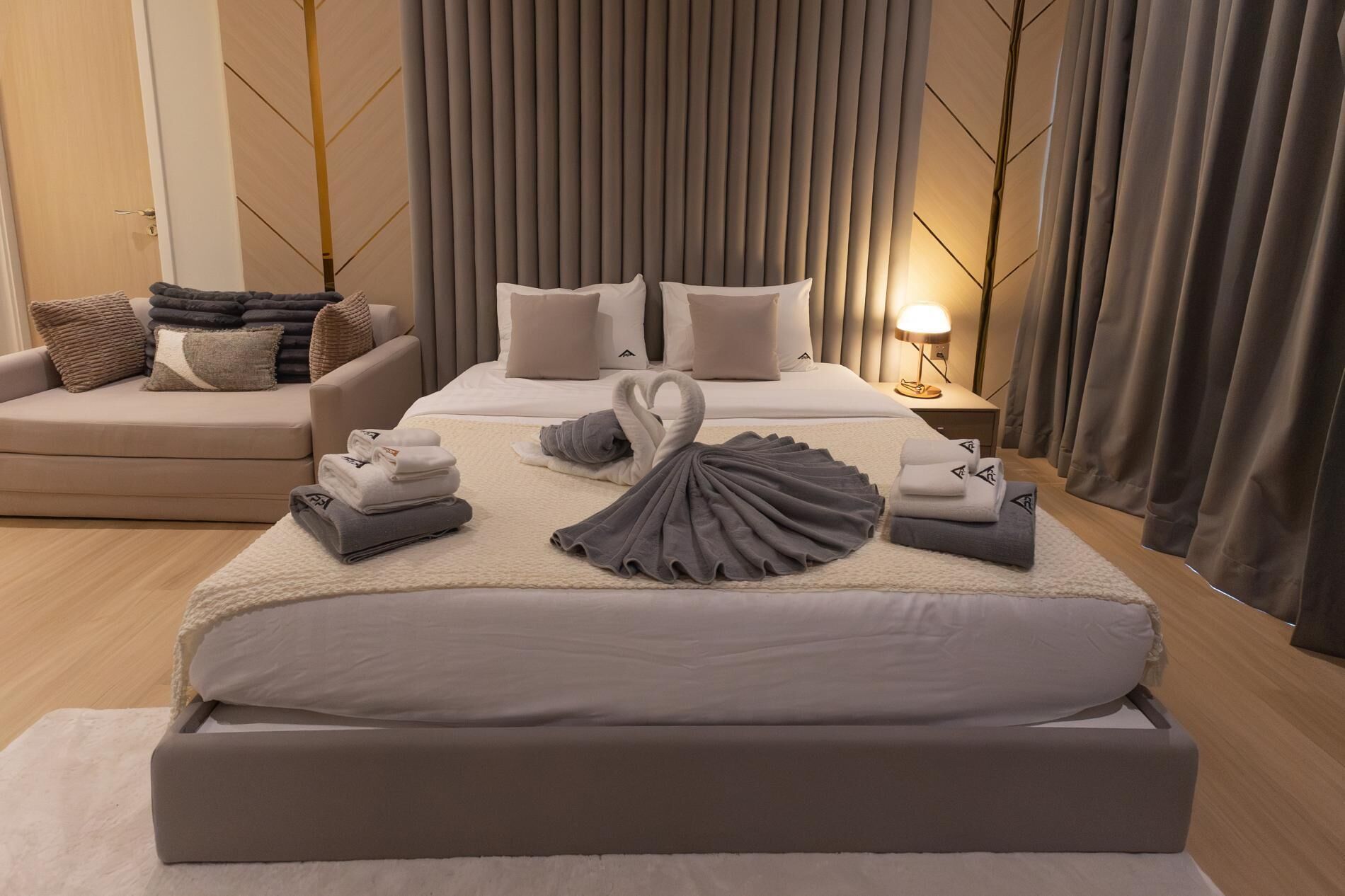 Une chambre d’hôtel moderne avec un grand lit, un canapé et une table de chevet avec une lampe.