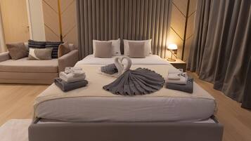 Une chambre d’hôtel moderne avec un grand lit, un canapé et une table de chevet avec une lampe.