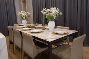 Une table à manger dressée avec des assiettes, des vases de fleurs et un miroir.