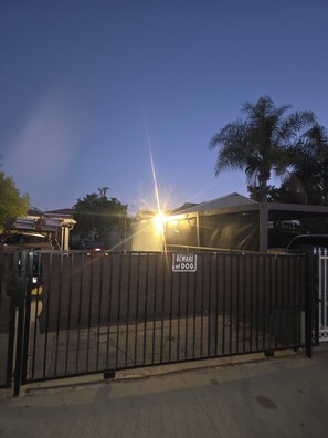 A gated area with a 'Beware of Dog' sign, a palm tree, and a building in the background. - Tranquil studio with AC in charming Hawthorne perfect for getaway (Hawthorne)