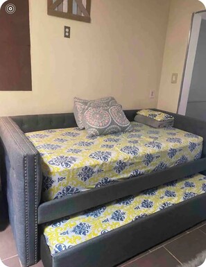 A bed with a patterned bedspread, two pillows, and a bedside table with a lamp. - Tranquil studio with AC in charming Hawthorne perfect for getaway (Hawthorne)