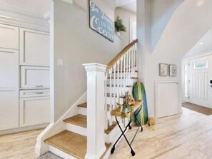 A staircase with a wooden finish, a white railing, and a small table with a plant.