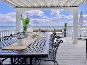 An outdoor seating area with a table and chairs, a pergola, and a view of the sea.