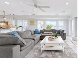 A modern living room with a sectional sofa, a coffee table, and a ceiling fan.