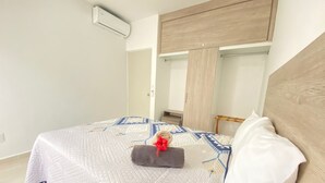 Een slaapkamer met een bed, nachtkastje, kledingkast en spiegel.