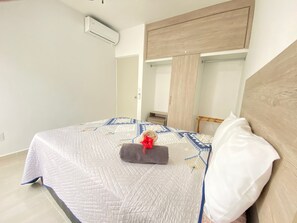 A bedroom with a bed, a nightstand, a wardrobe, and a mirror. - Apartment in the Mayakoba area for 8 people, including a SUV, for 7 days (Playa del Carmen)